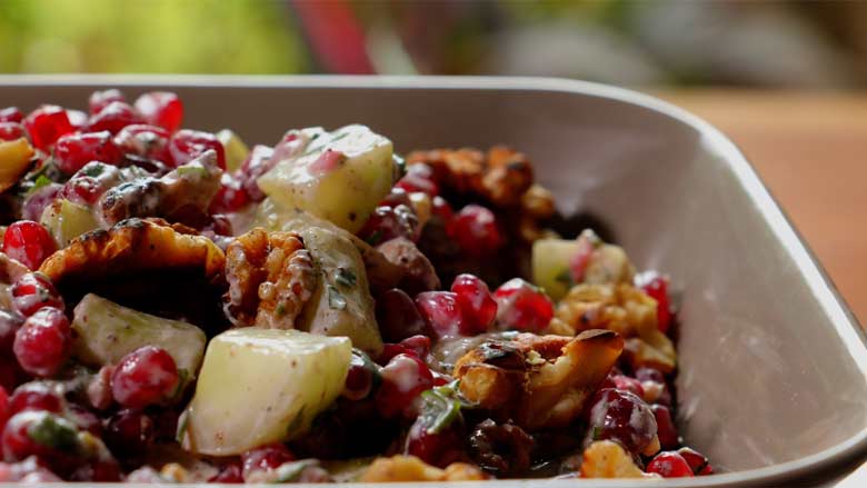 A close up side shot of Konkani Cucumber and Pomegranate Salad topped with toasted California walnuts in a square grey ceramic bowl with a blurred out background - Easy Konkani Cucumber and Pomegranate Salad Recipe